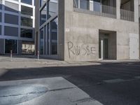 some graffiti has been written on the side of a building across from a parking lot