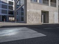 some graffiti has been written on the side of a building across from a parking lot