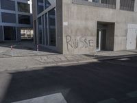 some graffiti has been written on the side of a building across from a parking lot