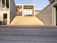 the large, empty sidewalk with multiple columns in front of the building with two signs