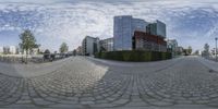 an 360 - view lens shows a man skateboarding in front of a building on a clear day