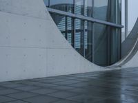 a person walking in the rain in front of an architectural building with windows on either side