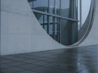 a person walking in the rain in front of an architectural building with windows on either side