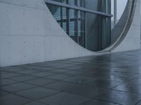 a person walking in the rain in front of an architectural building with windows on either side