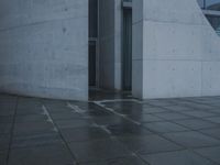 a person walking in the rain in front of an architectural building with windows on either side