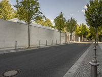 the street is lined with trees by the white walls and concretes on each side