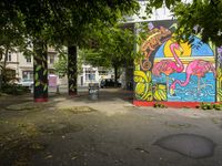 colorful painting on the side of a pole near trees and cars parked along it in front of a building in berlin, germany