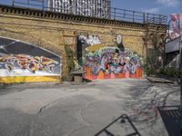 a brick wall with graffiti and an orange gate and fenced in area in front of it