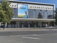 a building with glass fronting on both sides of the street and the word'techclr'across the front, is very large poster overhang a sidewalk