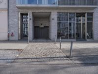 an entrance to a building on the corner of a road with cars passing by it