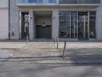 an entrance to a building on the corner of a road with cars passing by it
