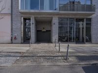 an entrance to a building on the corner of a road with cars passing by it