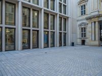 an empty brick courtyard area with two stone columns and two arched windows in the background