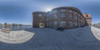 a fish eye lens picture of a bench and a building next to water in front of the city