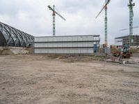 a small construction site with a bull parked by it and some cranes hanging from the building