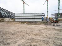 a small construction site with a bull parked by it and some cranes hanging from the building