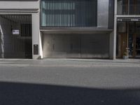 a man is standing on the sidewalk by a building that looks like it has two large garages