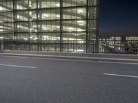 a very wide view of an empty road in front of a building with glass and metal