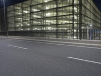 a very wide view of an empty road in front of a building with glass and metal