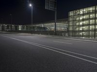 a very wide view of an empty road in front of a building with glass and metal