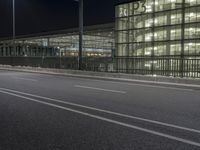 a very wide view of an empty road in front of a building with glass and metal