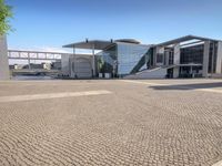 brick paving in front of an open, modern building with a triangular roof area on it