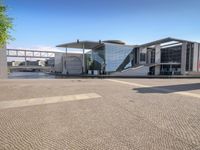 brick paving in front of an open, modern building with a triangular roof area on it