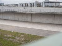 a man riding a skateboard down the side of a cement covered road next to a green grass field