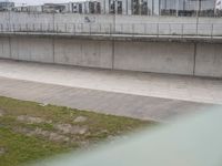 a man riding a skateboard down the side of a cement covered road next to a green grass field