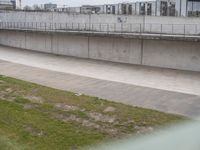 a man riding a skateboard down the side of a cement covered road next to a green grass field