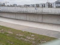 a man riding a skateboard down the side of a cement covered road next to a green grass field