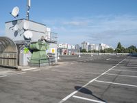 a green and white device sitting in a parking lot near buildings and trees, and a radio antenna