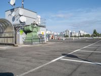 a green and white device sitting in a parking lot near buildings and trees, and a radio antenna