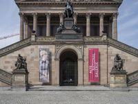 the entrance to the art gallery with the statue of a man holding a book and looking out to an open doorway