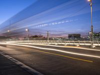 light streaks in the night sky as vehicles drive along a street at dusk on a city street