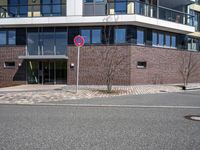 two buildings with glass walls are located near a street corner in the city with no cars parked in the area