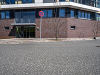 two buildings with glass walls are located near a street corner in the city with no cars parked in the area