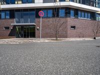 two buildings with glass walls are located near a street corner in the city with no cars parked in the area