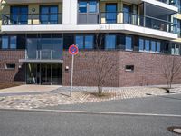 two buildings with glass walls are located near a street corner in the city with no cars parked in the area