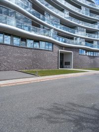 an image of a big building on the side of the street - some building behind it is a green grassy field