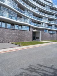 an image of a big building on the side of the street - some building behind it is a green grassy field