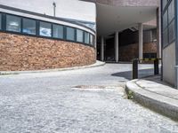 a parking area on the side of a building with tall windows and a bench on the side