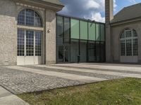 the outside side of a building with a clock tower in the background and green grass on the ground near it