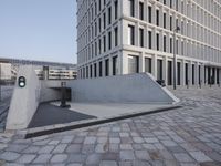 a stone walkway leading into a building in the background has white walls with large windows