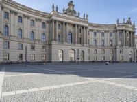 an image of a building in germany with many doors on each side and a person walking across the courtyard