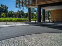 a road through which is a large modern building with an awning over it's entrance