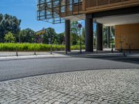 a road through which is a large modern building with an awning over it's entrance