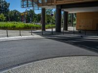 a road through which is a large modern building with an awning over it's entrance