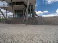 a person on a bike walking through a stone building entrance, in front of an enormous glass wall and stairs