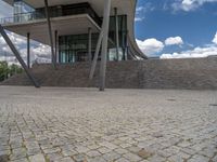 a person on a bike walking through a stone building entrance, in front of an enormous glass wall and stairs